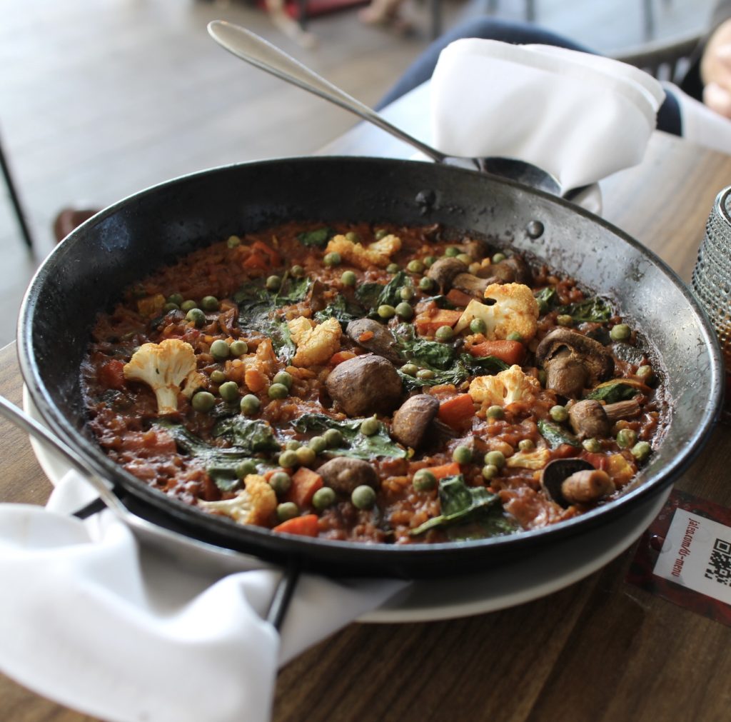 Vegetable paella in a black dish pan on a table at Jaleo