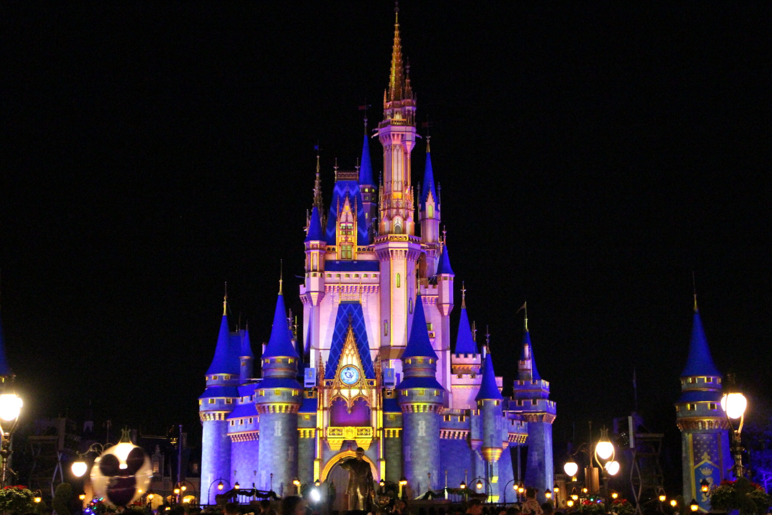 a dark night sky surrounds the Disney castle illuminated at Magic Kingdom