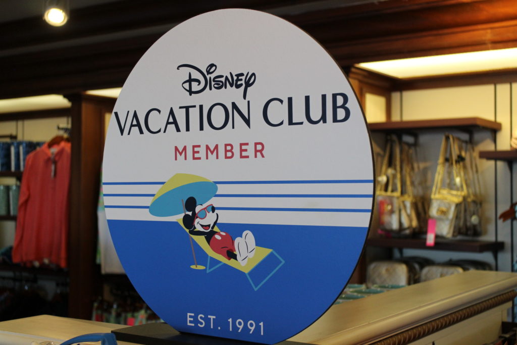 Circular Disney Vacation Club Member sign in a shop with Mickey on it lounging under an umbrella