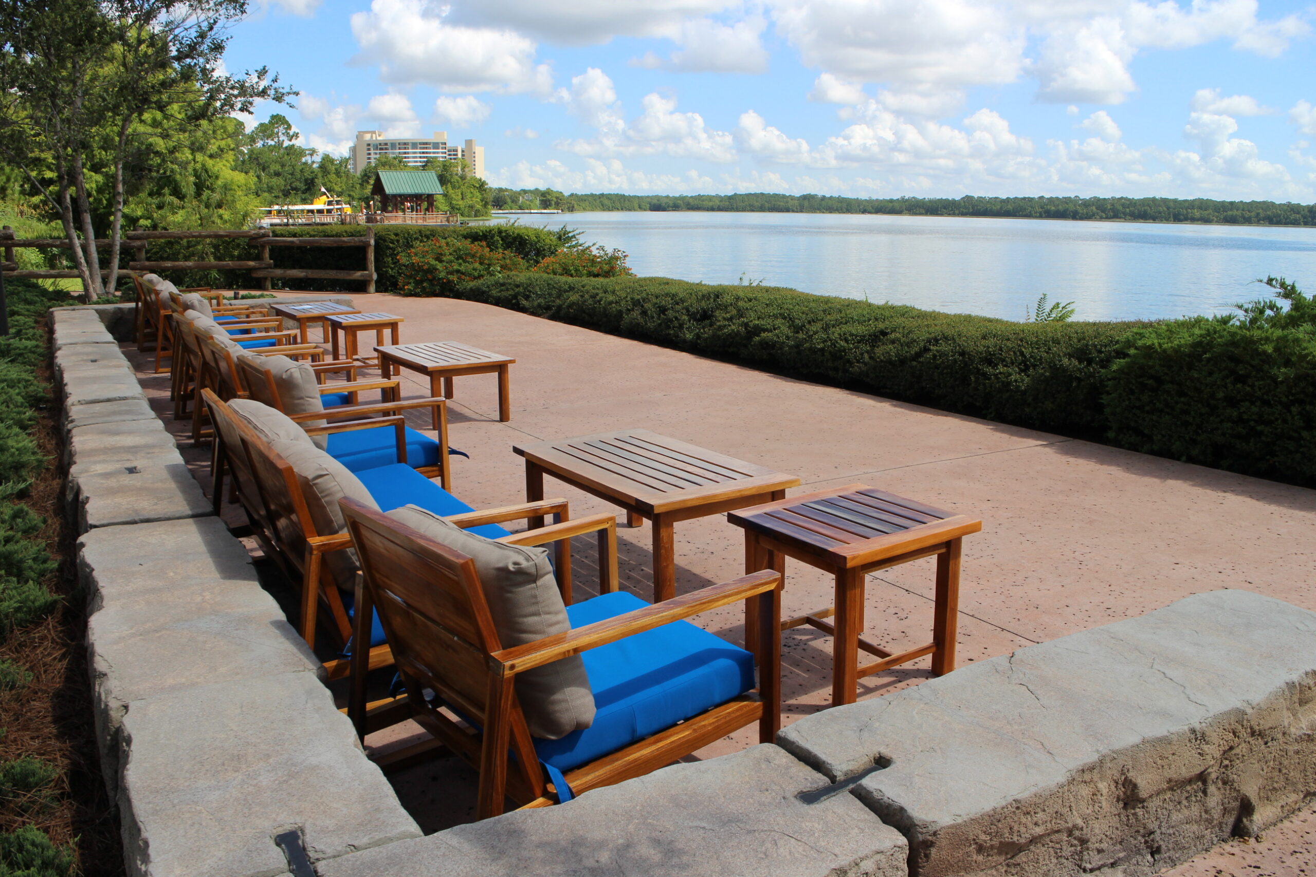 Wooden chairs and tables on an outdoor patio that overlooks Bay Lake, seating behind Geyser Point Bar and Grill