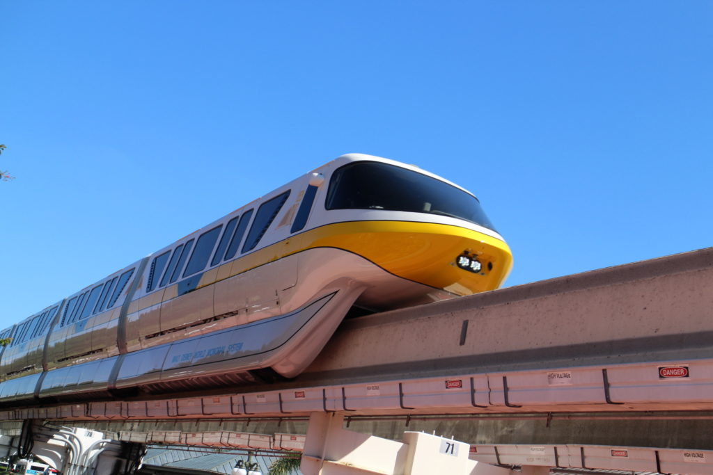 white monorail with yellow stripe on a beam against a blue sky Disney World news