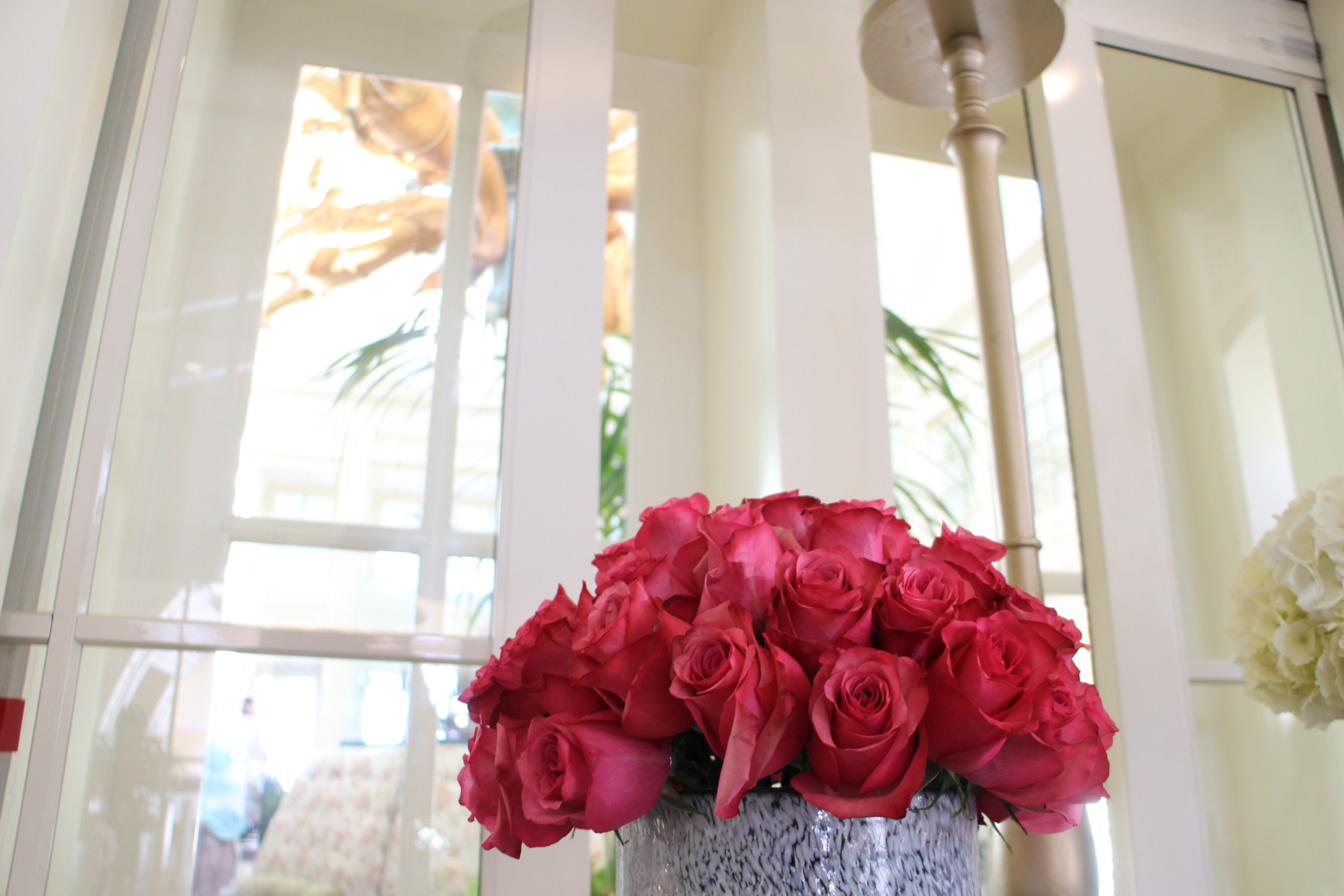 Fuschia roses in a vase in front of a crisp white entry way at Disney's BoardWalk Resort