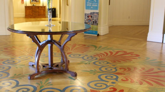 ornate pattern on wood floor under a round table with a plant in the Disney's Beach Club Villas lobby