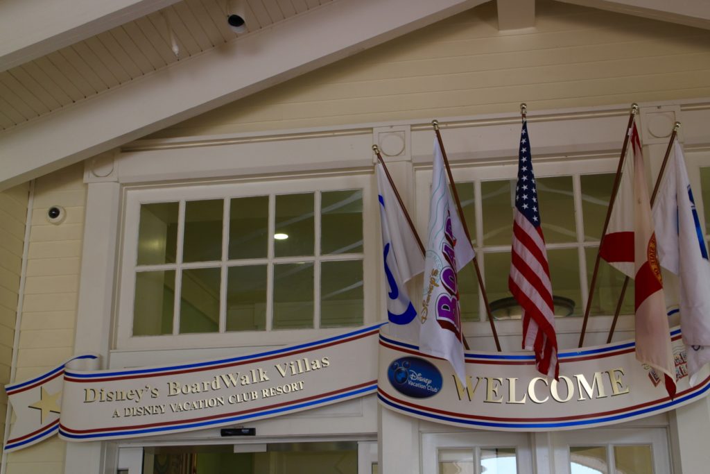 View above the entrance doors of Disney's BoardWalk resort with flags hanging, windows and a Disney's BoardWalk Villas sign