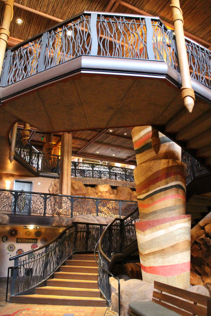 An earth tone spiral staircase surrounded by detailed rock work an a water feature at Disney's Animal Kingdom Lodge