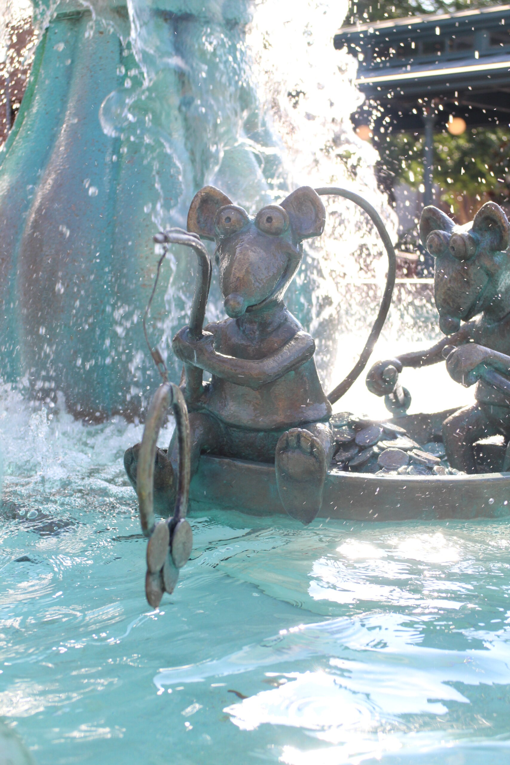 A Muppet rat statue closeup in a splashy water fountain