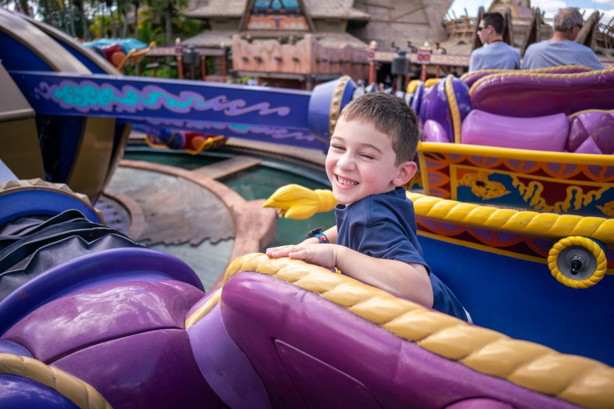 young boy riding a ride at a theme park