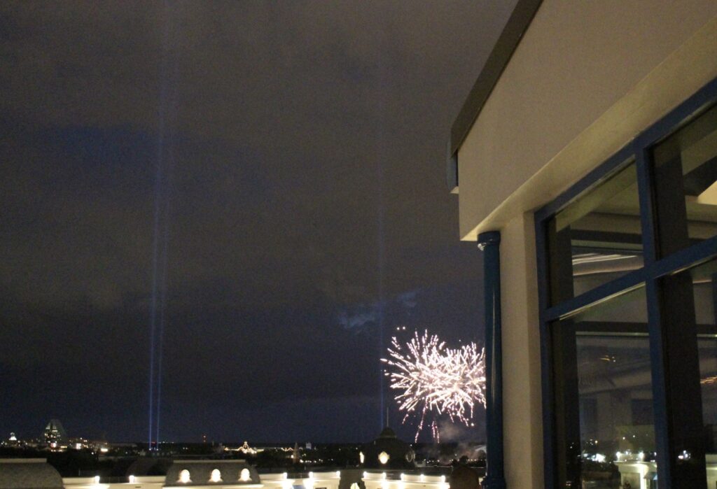 A rooftop view of Epcot's fireworks against a dark sky from Topolino's Terrace at Disney's Riviera Resort