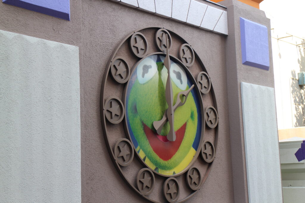 Kermit the Frog's face as the background of a clock on an outdoor wall at Disney's Hollywood Studios