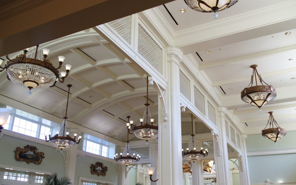 A rounded white ceiling with intricate wood beams and lots of glitzy chandeliers in the DVC resort Disney's BoardWalk