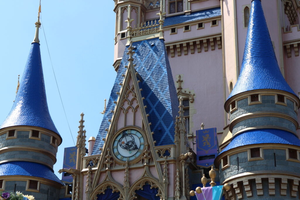 Cinderella Castle close up with blue cone shaped towers and gold detailing around an ornate clock.