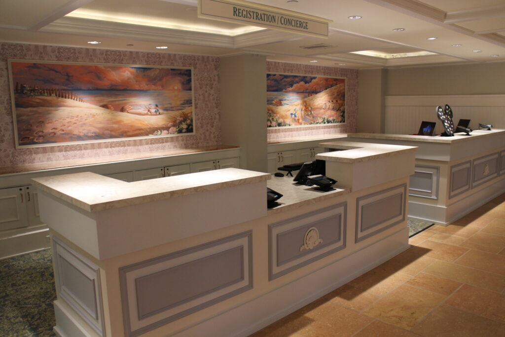 Beach Club lobby after refurbishment in 2023 with new pastel beach art behind the desks featuring fab five characters