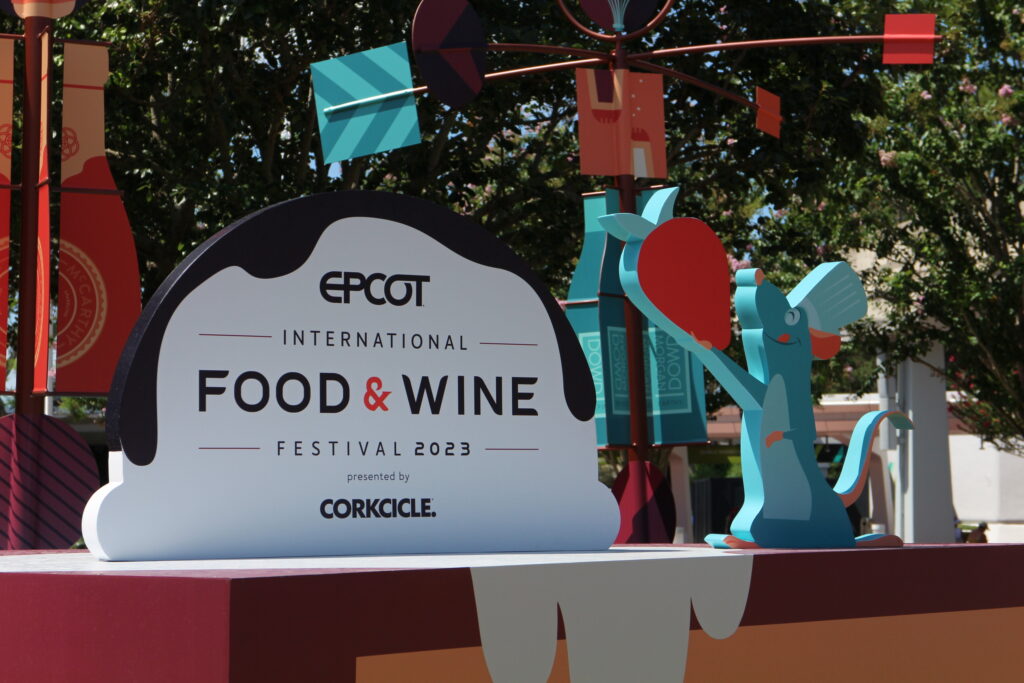 Epcot International Food and Wine entrance set up 2023 with Remy the rat holding a strawberry and an ice cream scoop shaped event sign