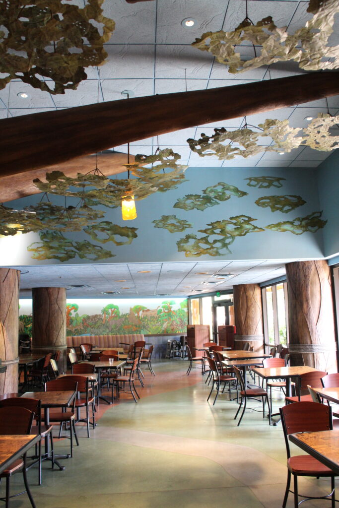 Seating inside a brightly lit quick service restaurant with shiny, earth tone floors and a tree inspired ceiling