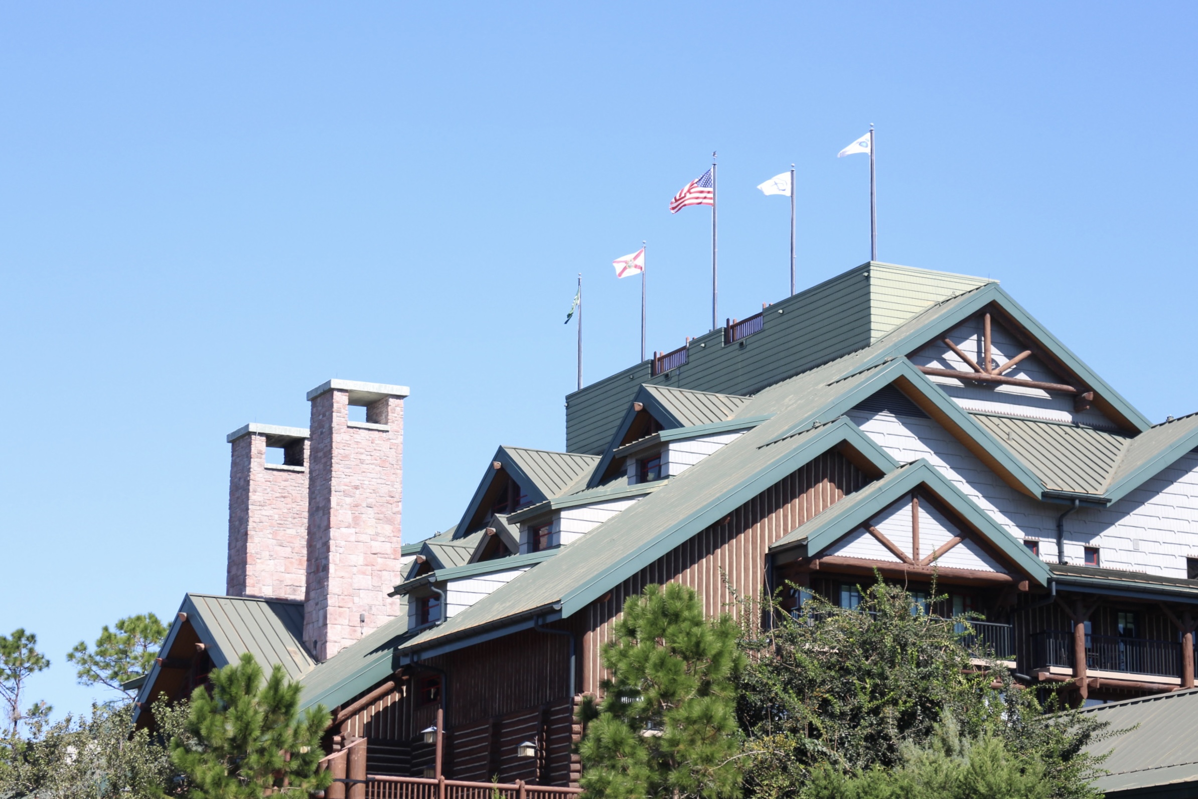 Green roof on the Wilderness Lodge lobby building with chimneys in front of a blue sky