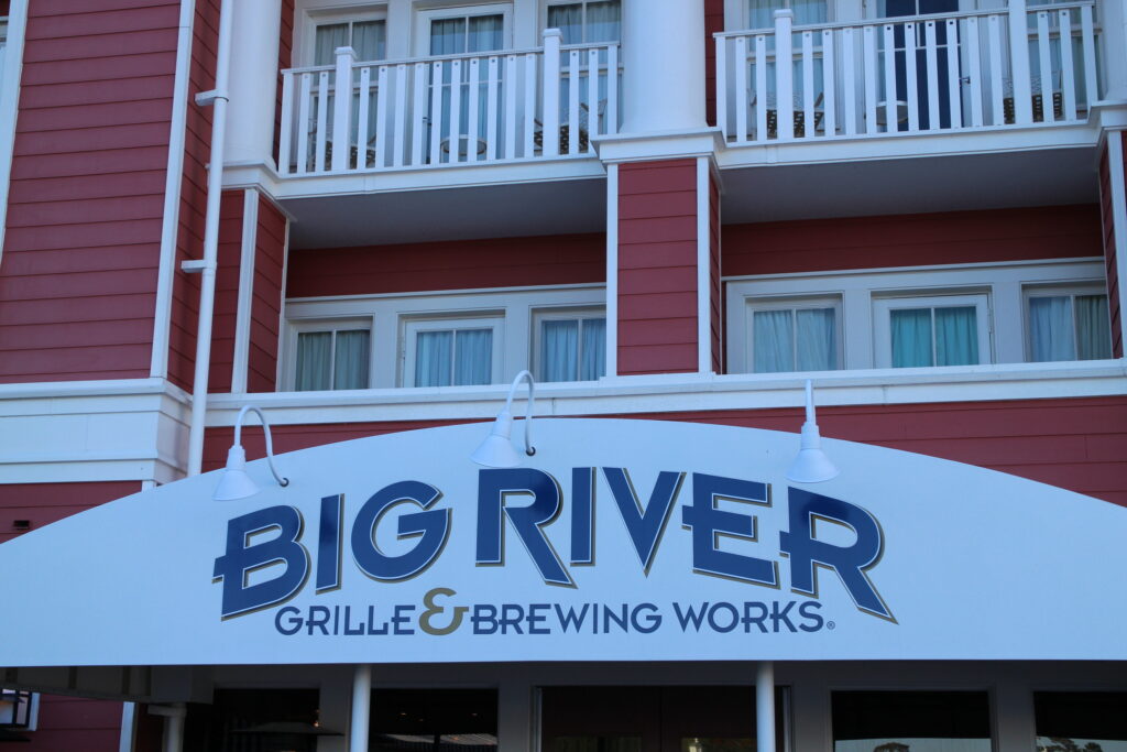 White Big River Grille and Brewing Works sign with blue lettering on Disney BoardWalk building