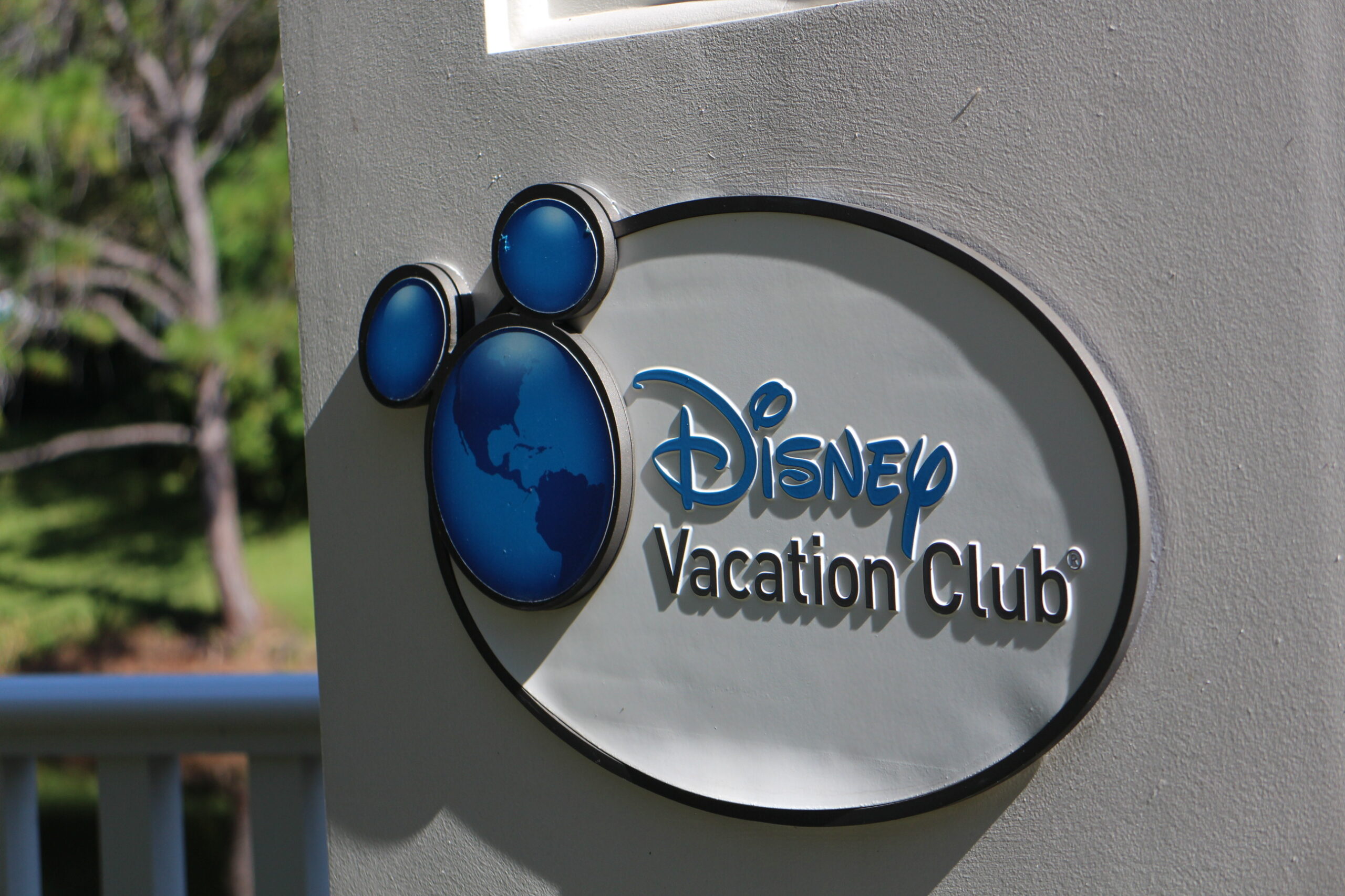 white Disney Vacation Club emblem with globe logo on a wall outdoors