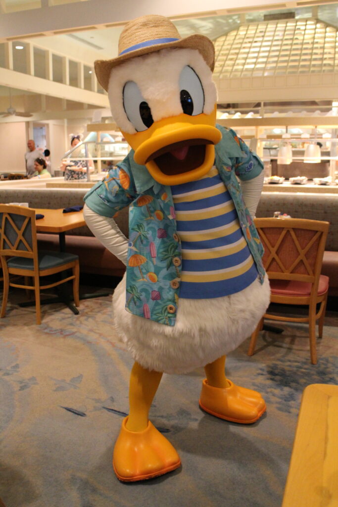 Donald Duck stands in beachy attire inside Cape May Cafe's coastal atmosphere buffet