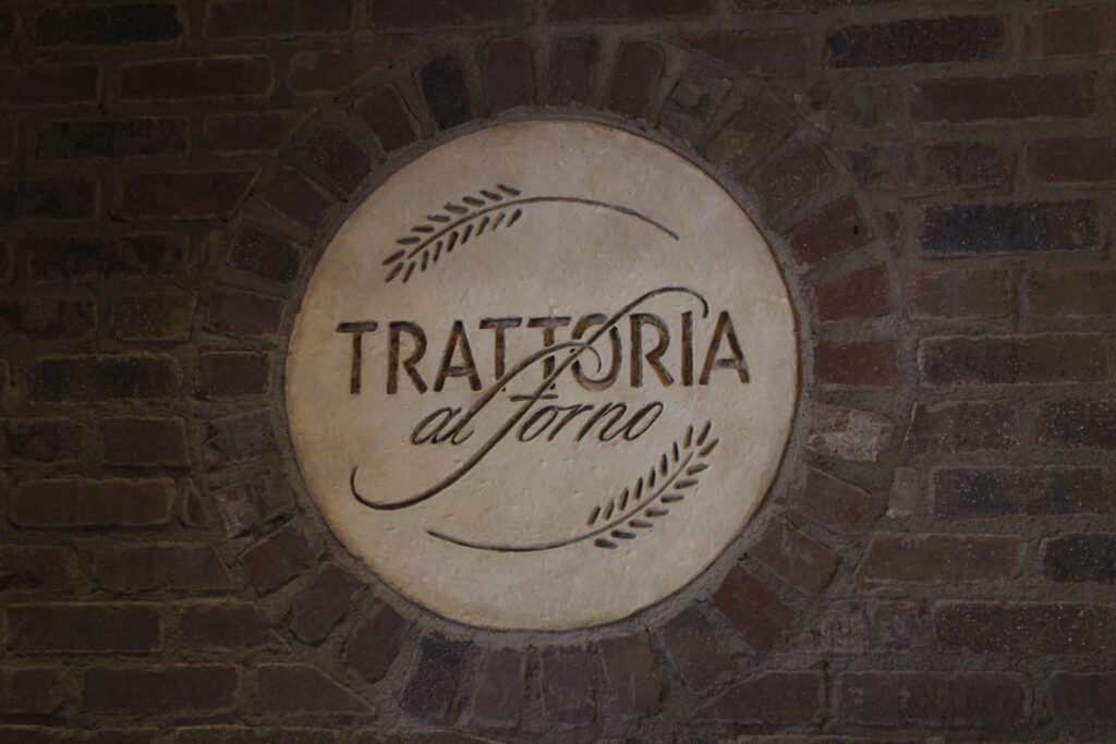 Trattorial al Forno sign with words carved into cement circle on a brick wall