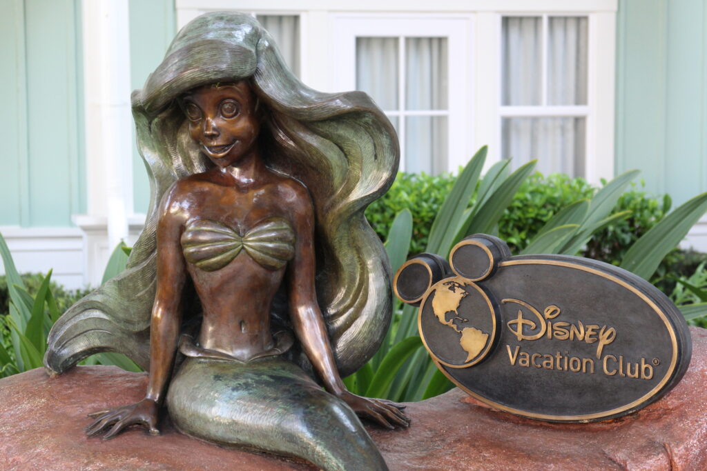 A bronze colored statue of Ariel the little mermaid next to a Disney Vacation Club sign