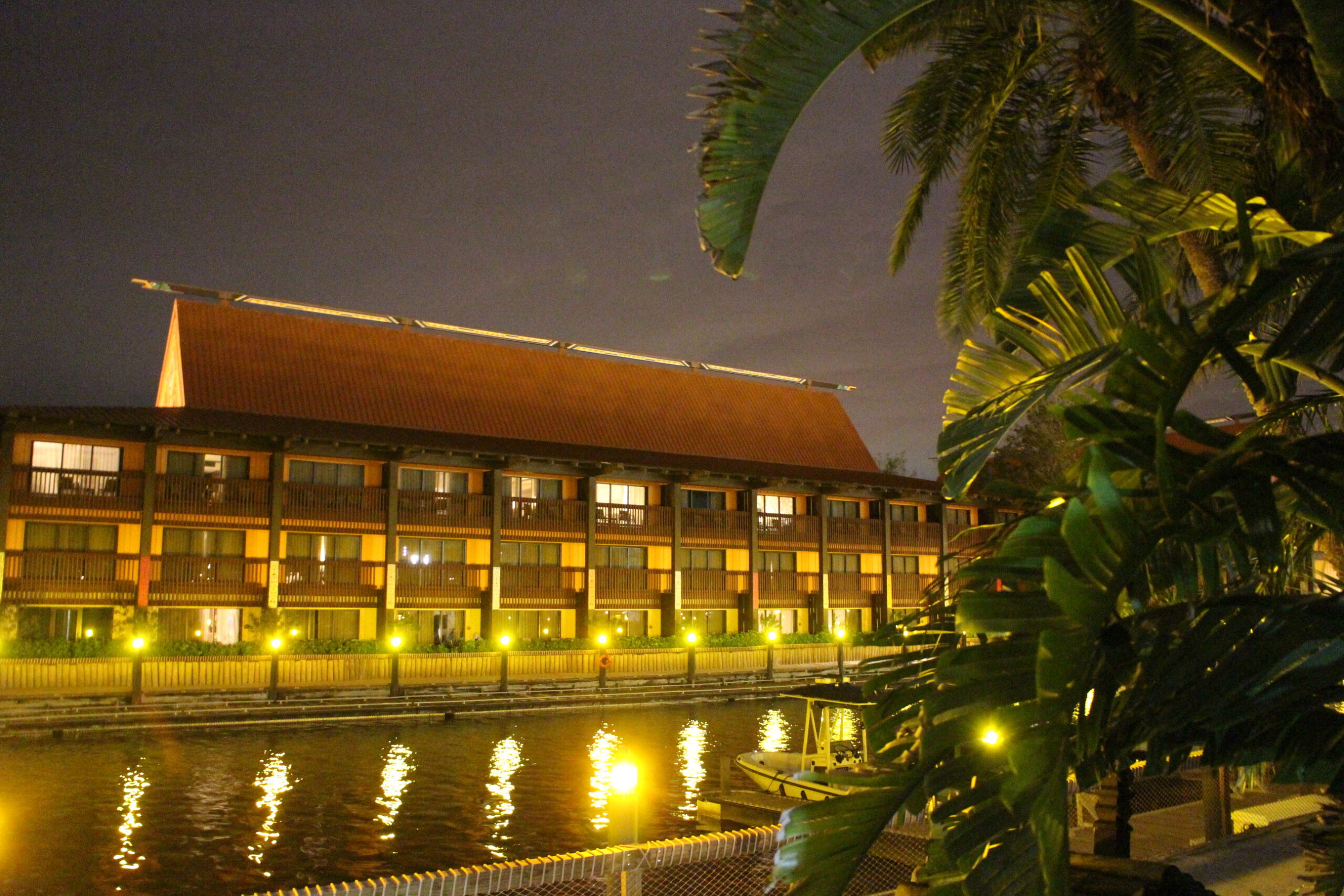 a building glows with lights behind the marina at the Polynesian resort