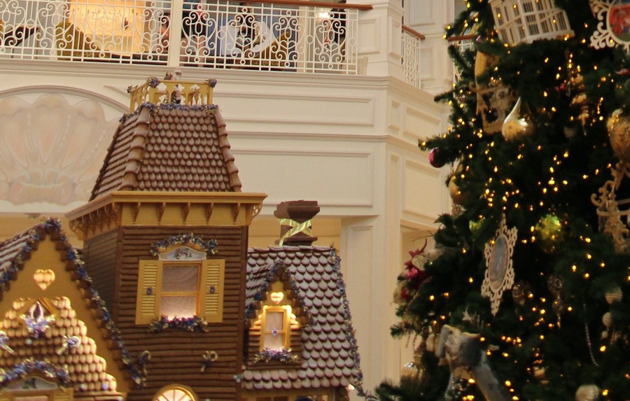 Grand Floridian Gingrbread House peeking out from behind the resort's massive Christmas tree