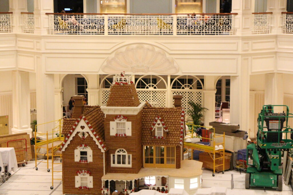 A mostly constructed gingerbread house sits tall in the white Grand Floridian lobby