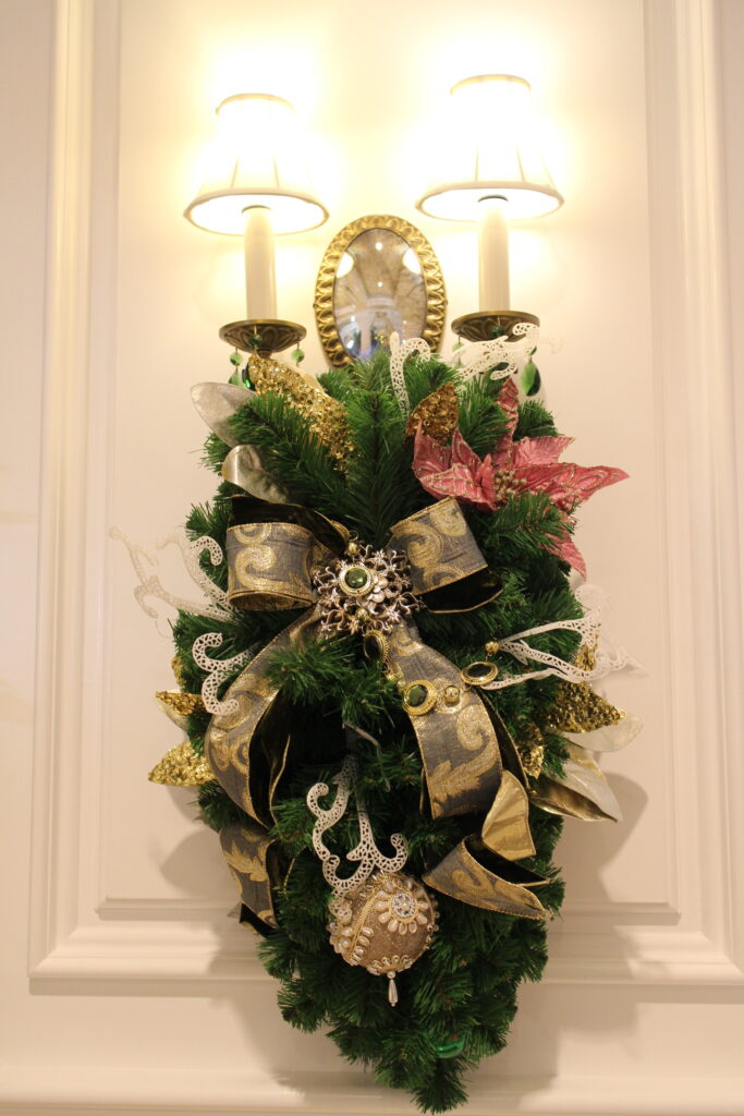Grand Floridian Villas Christmas decor, a branch, green spray on a white wall with two sconces
