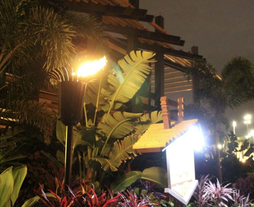The Polynesian at night with foliage lit by a tiki torch