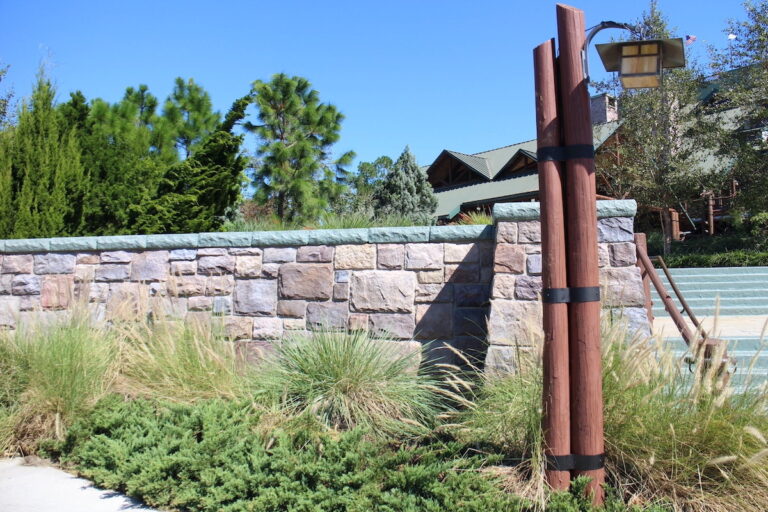 The front of Wilderness Lodge with a stone wall and woodsy and green landscaping