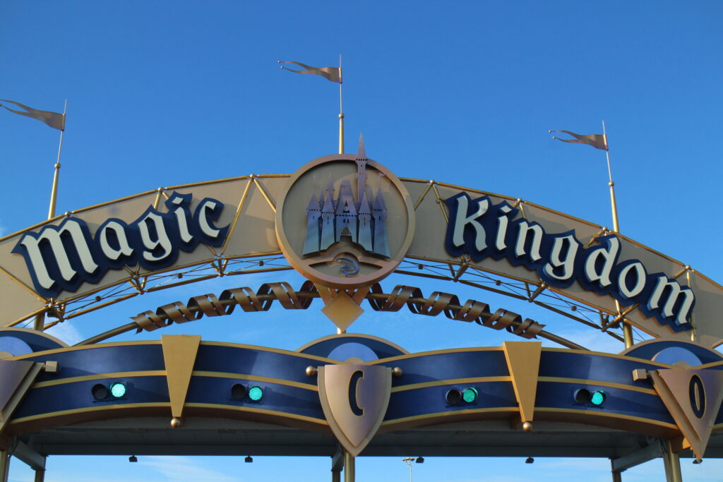 a gold and blue Magic Kingdom sign closeup with a castle in the middle 