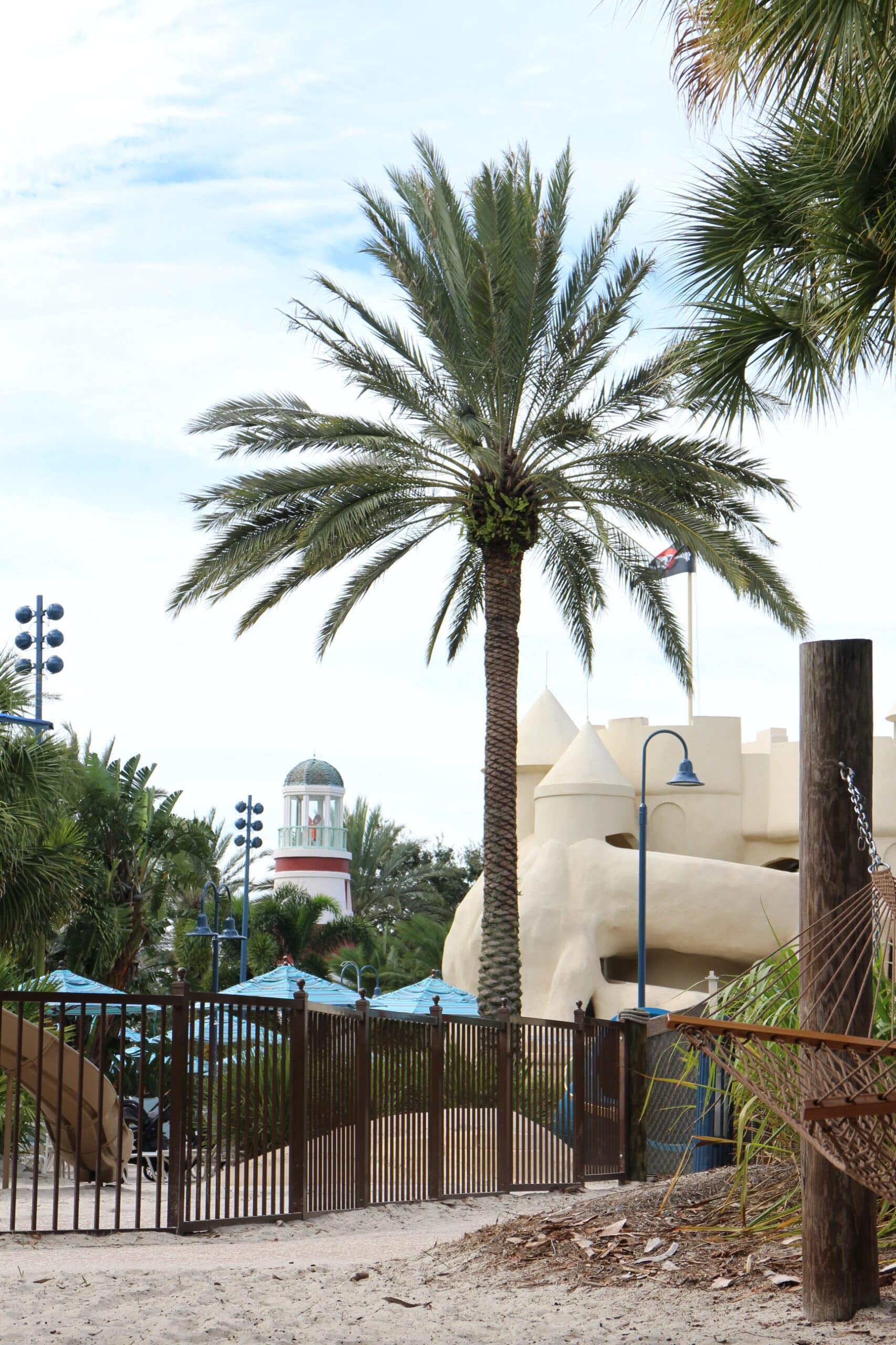 a palm tree stands with the Old Key West pool icons off in the distance: a lighthouse and a sandcastle where the water slide comes out of