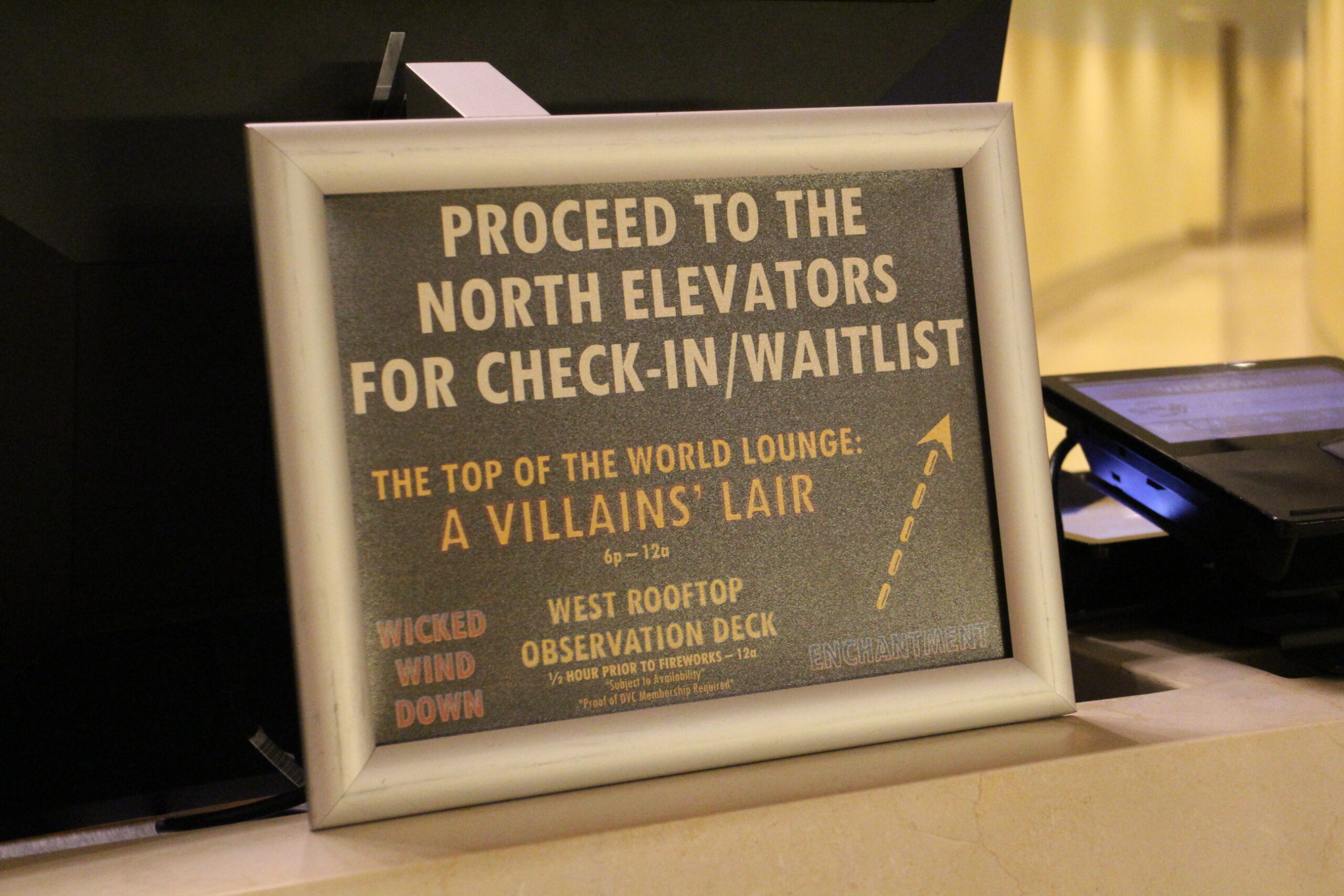 a sign on a desk that says proceed to the North elevators for check in/waitlist for Top of the World Lounge DVC