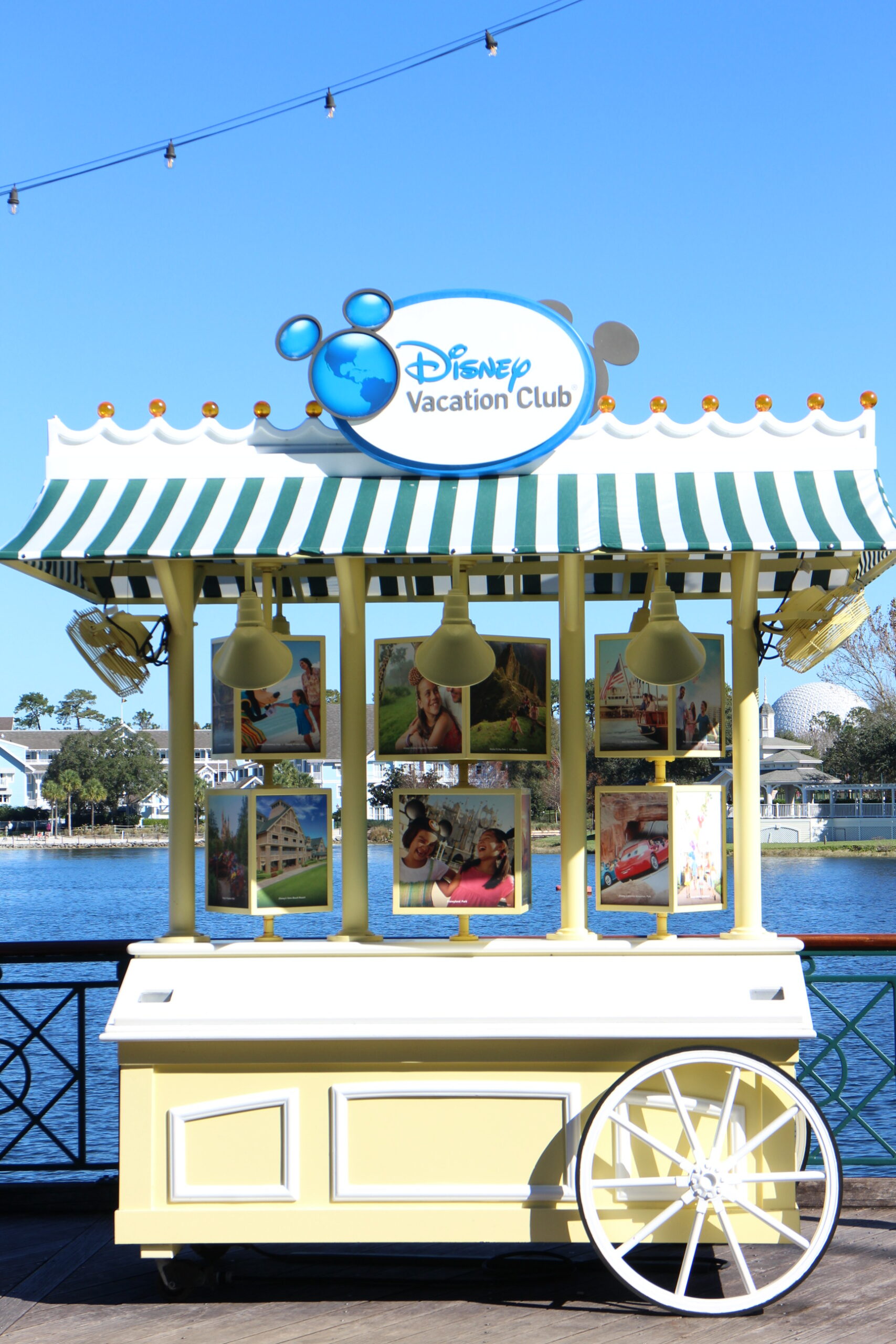a Disney Vacation Club information cart with a blue and white striped awning