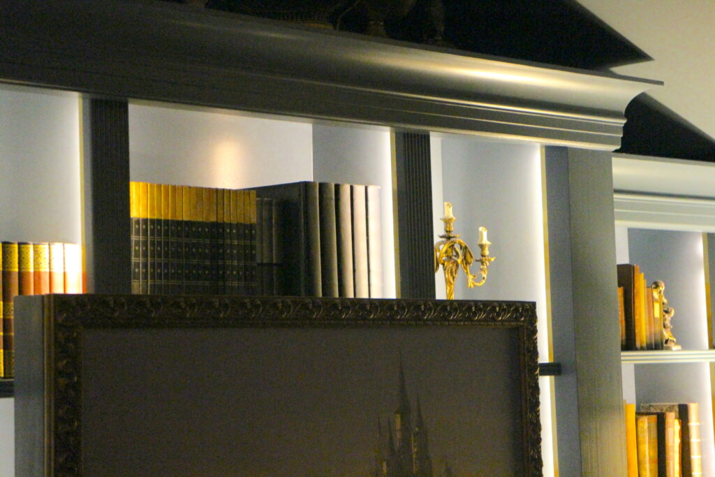 A bookshelf with the live action Lumiere on the top shelf.