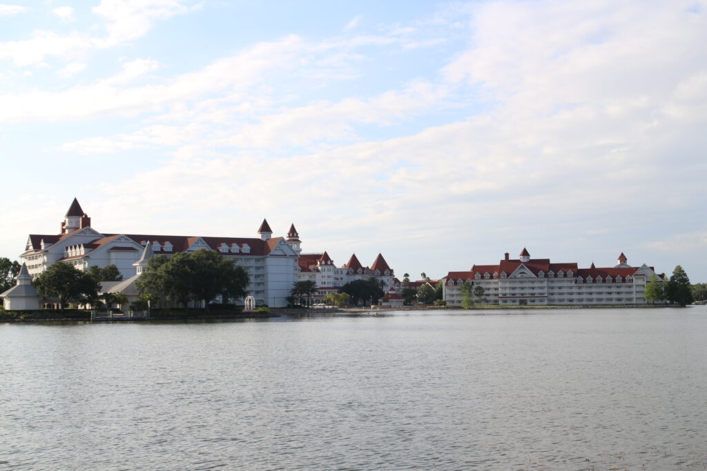 a lake with the white buildings and red roofs of the Grand Floridian behind it