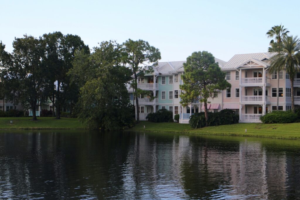 A dark pond reflects pastel, three story hotel buildings of DVC resort Old Key West.