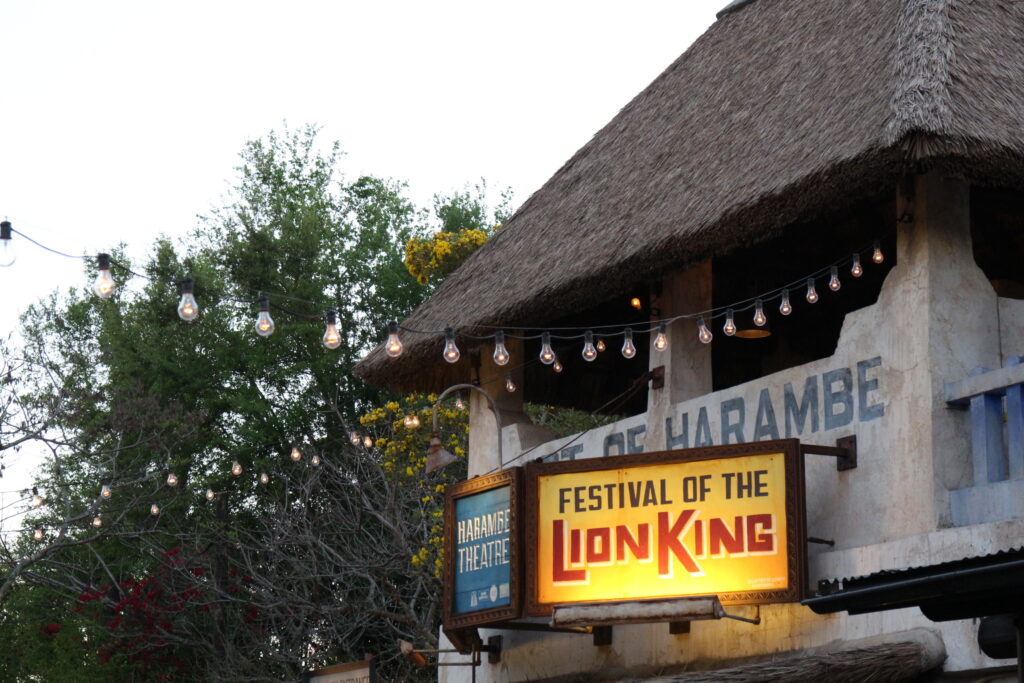 An African themed building with string lights out front and a sign that says Festival of The Lion King.