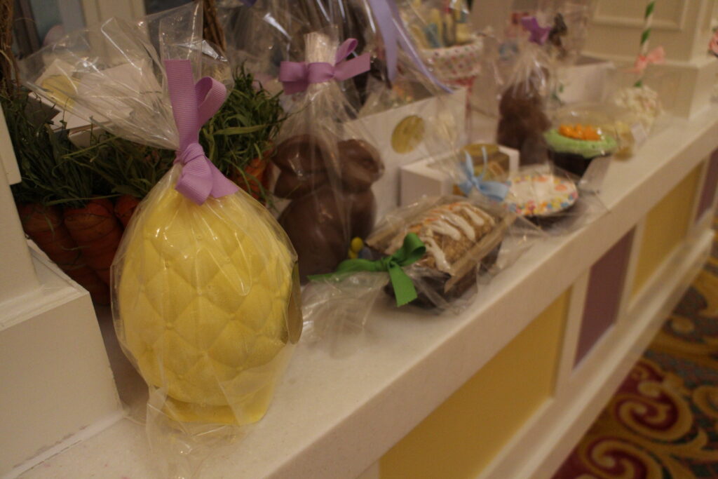 A display of treats for Easter like a large white chocolate egg wrapped in clear wrapping.