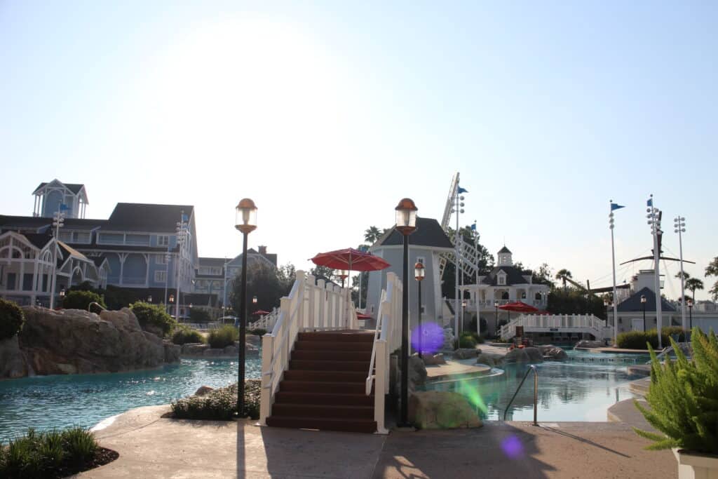 Sun flares glisten over the bridges, windmills and pool water of Stormalong Bay at Disney's Yacht and Beach Club Resort.