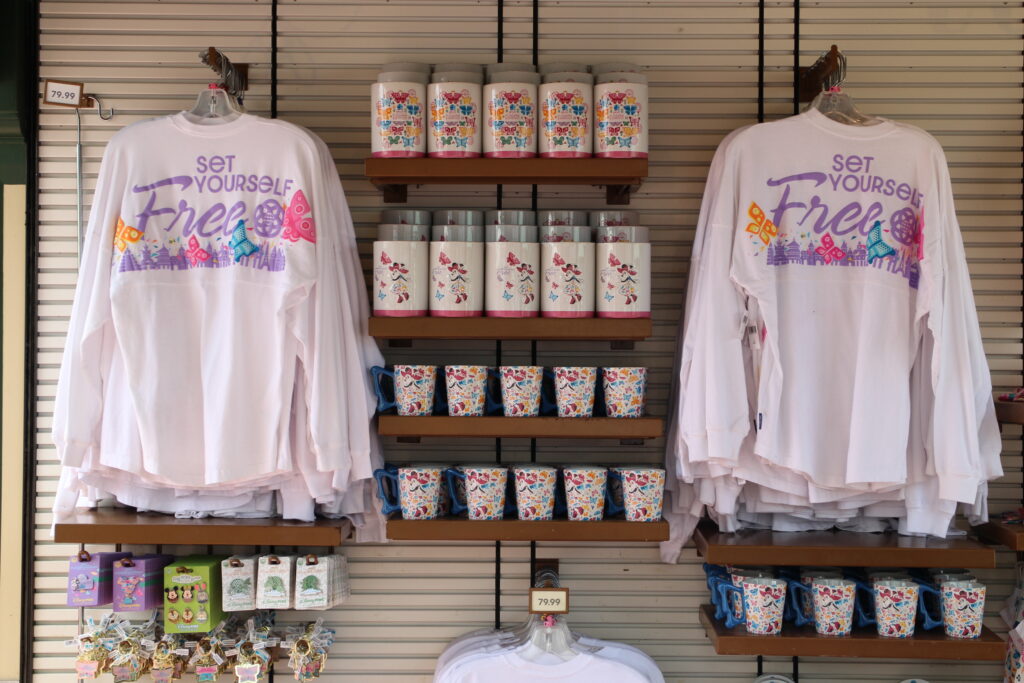 A display of Epcot Flower and Garden Festival merchandise including a white long sleeve t-shirt that says set yourself free on the back with butterflies.