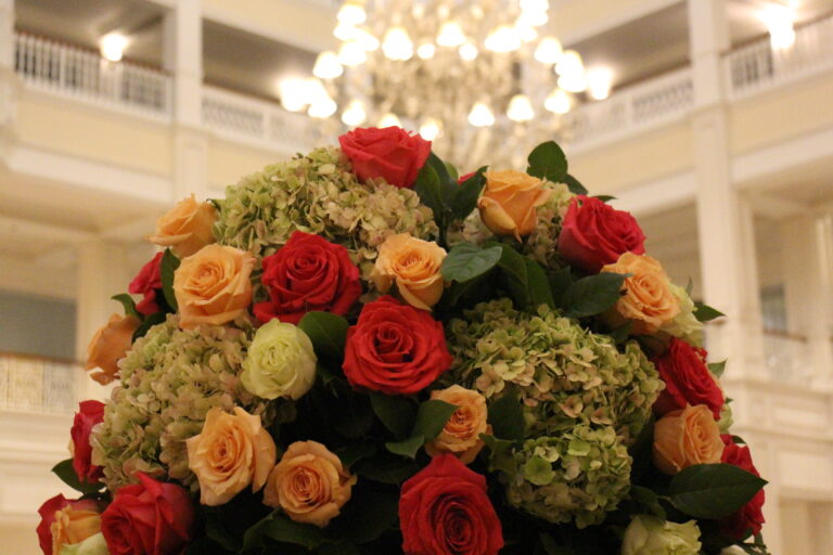 The Grand Floridian resort flowers with roses and hydrangeas and a bright, white chandelier in the background.